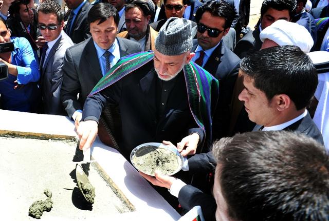 President Hamid Karzai pours mortar for starting a construction project