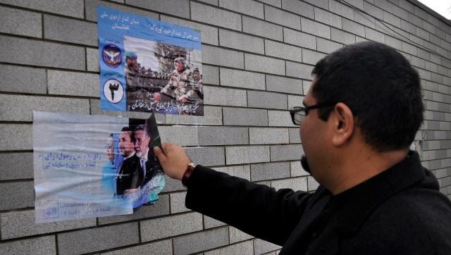 A resident removes poster of Zalmai Rassoul