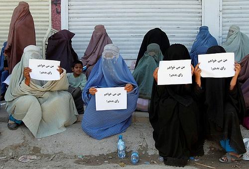 Burqa- clad women sit in front of a voter registration centre