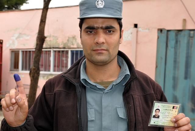 An Afghan National Police, shows his coloured finger and card