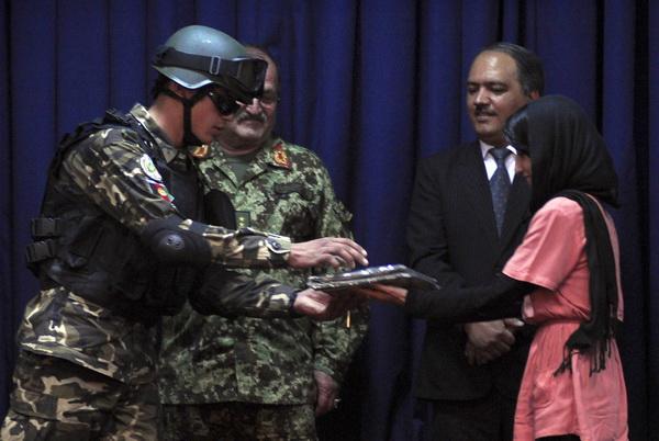 A female journalist awards a certificate to a soldier