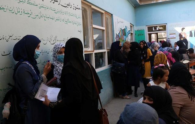 Women wait outside a polling station for voting