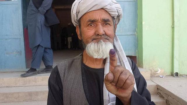 Elderly man shows colored finger after using vote