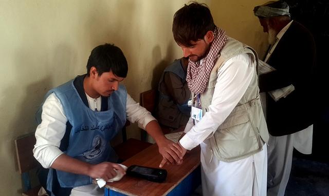 IEC worker takes fingerprint of a voter