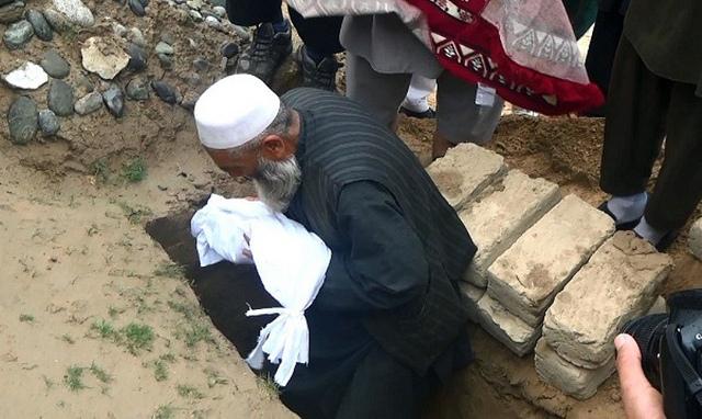 A man placing slain baby into grave