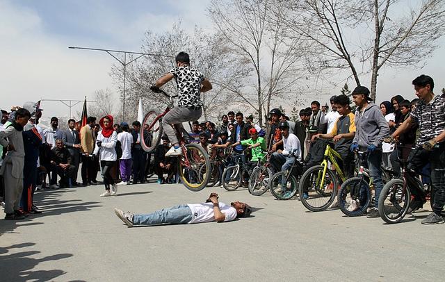Young boy jamps over a man with riding cycle